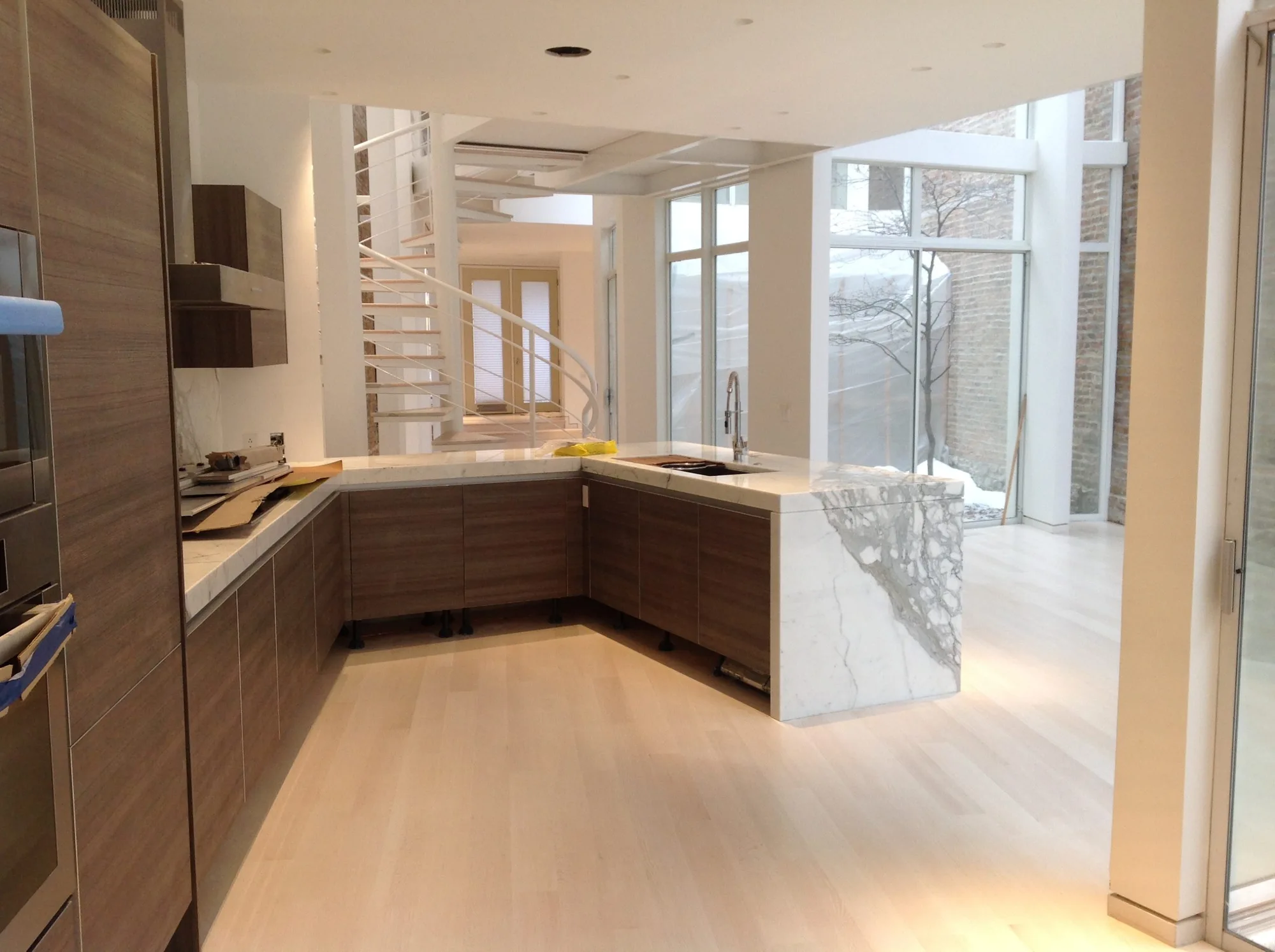 Pale plank flooring beneath a marble island and timber kitchen cabinetry.