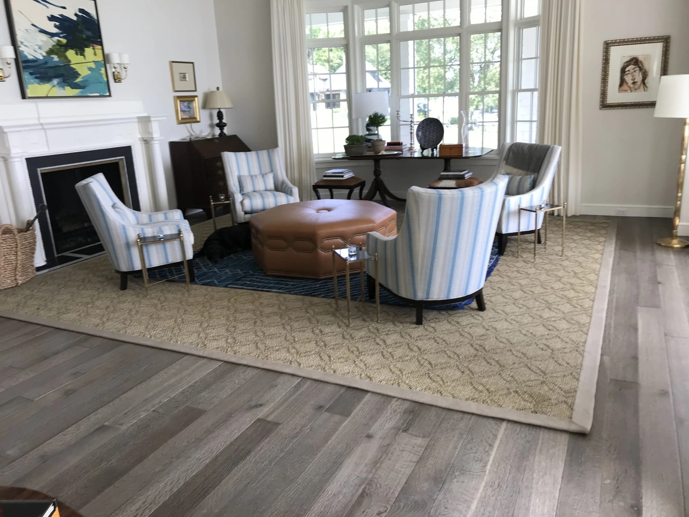 A furnished sitting room with sunlight falling across the wood floor.